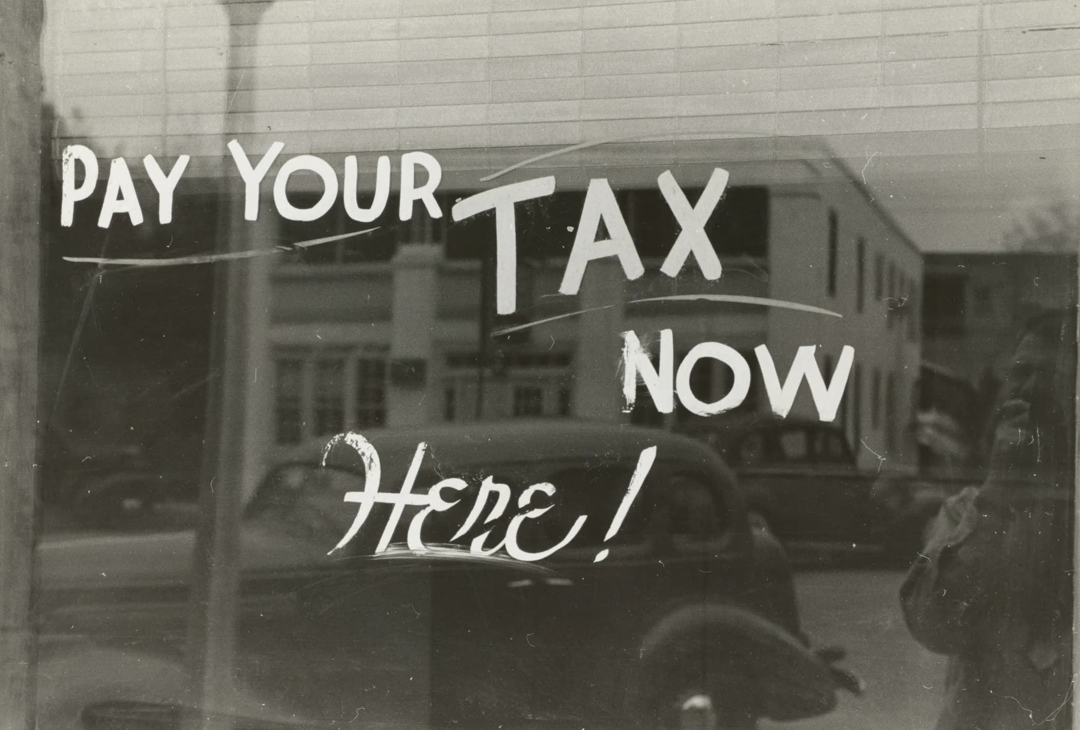 Cartello storico americano con scritta 'Pay Your Taxes Here' — tasse e ritenuta d'acconto per musicisti e lavoratori autonomi