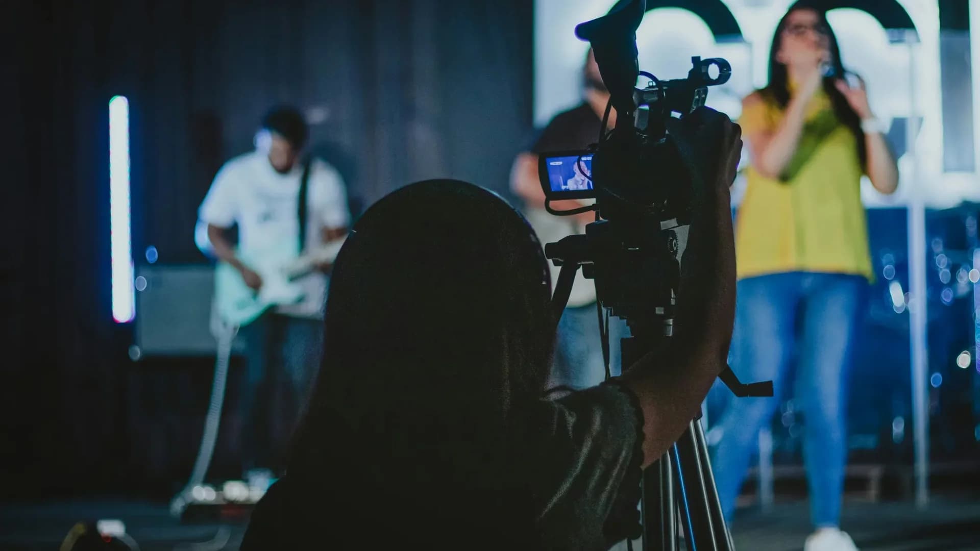 Videomaker che riprende musicista durante concerto dal vivo per video demo band matrimoni — registrazione professionale con telecamera e impianto audio